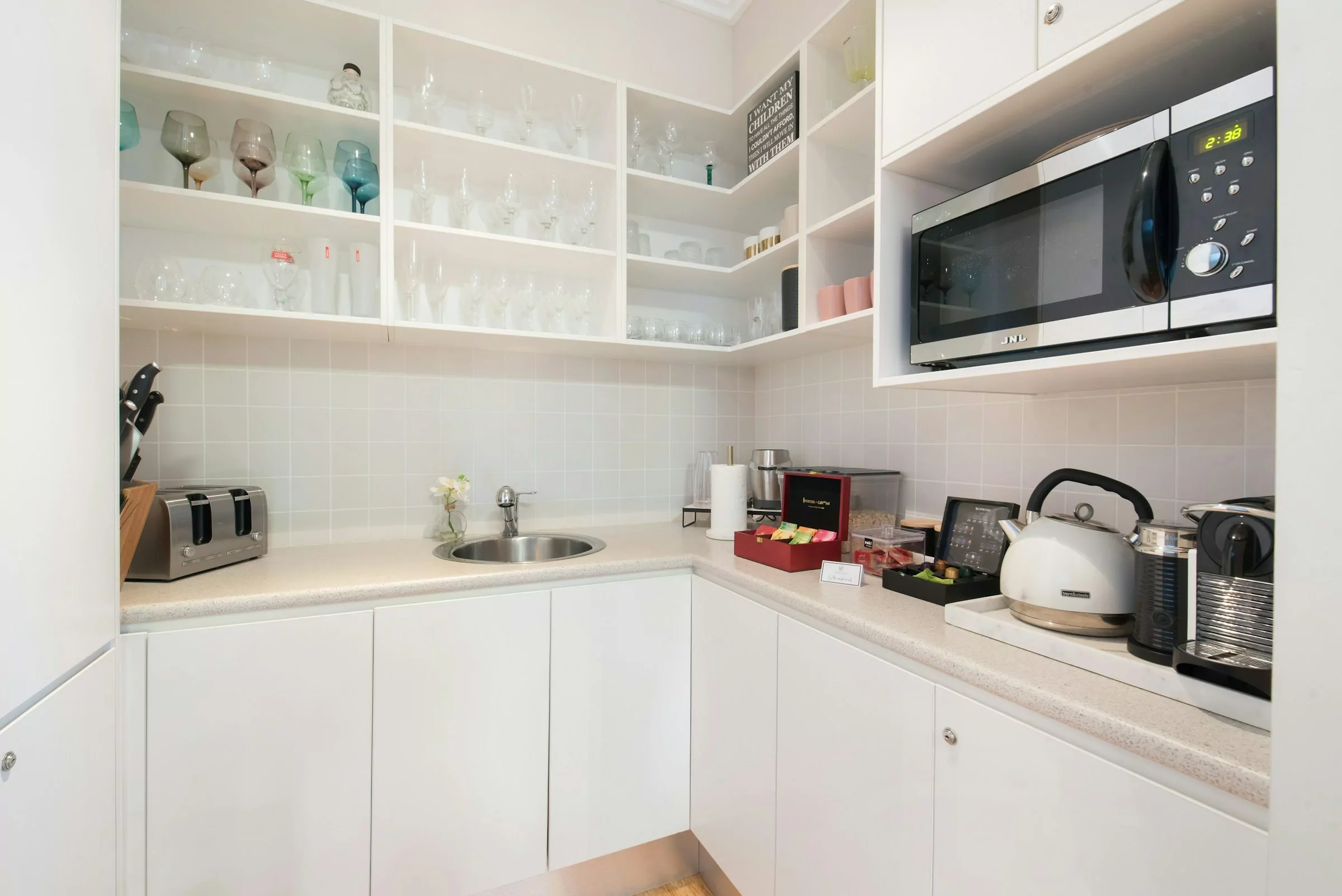 A bright and airy white kitchen with glossy cupboard doors, open cabinets and a modern, minimalist design.